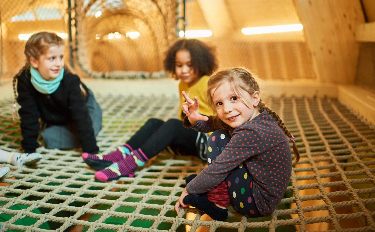 drei Kinder sitzen auf einem Netz