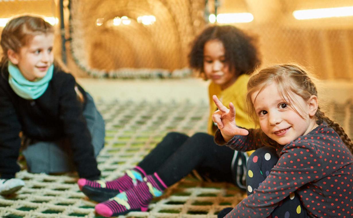 drei Kinder sitzen auf einem Netz