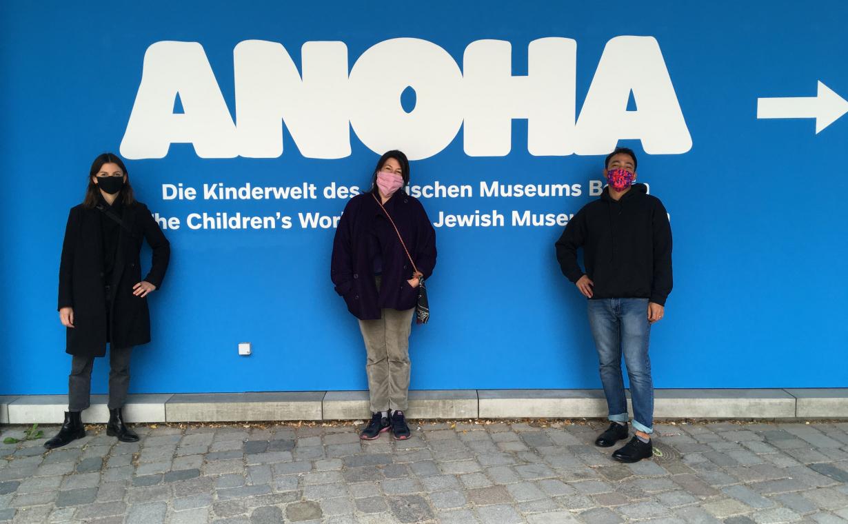 drei Menschen stehen vor einer Wand mit dem Schriftzug ANOHA