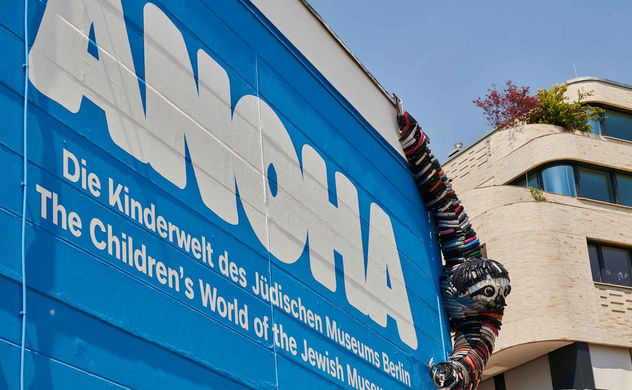 ANOHA lettering on a wall with a sloth hanging out made out of bicycle parts