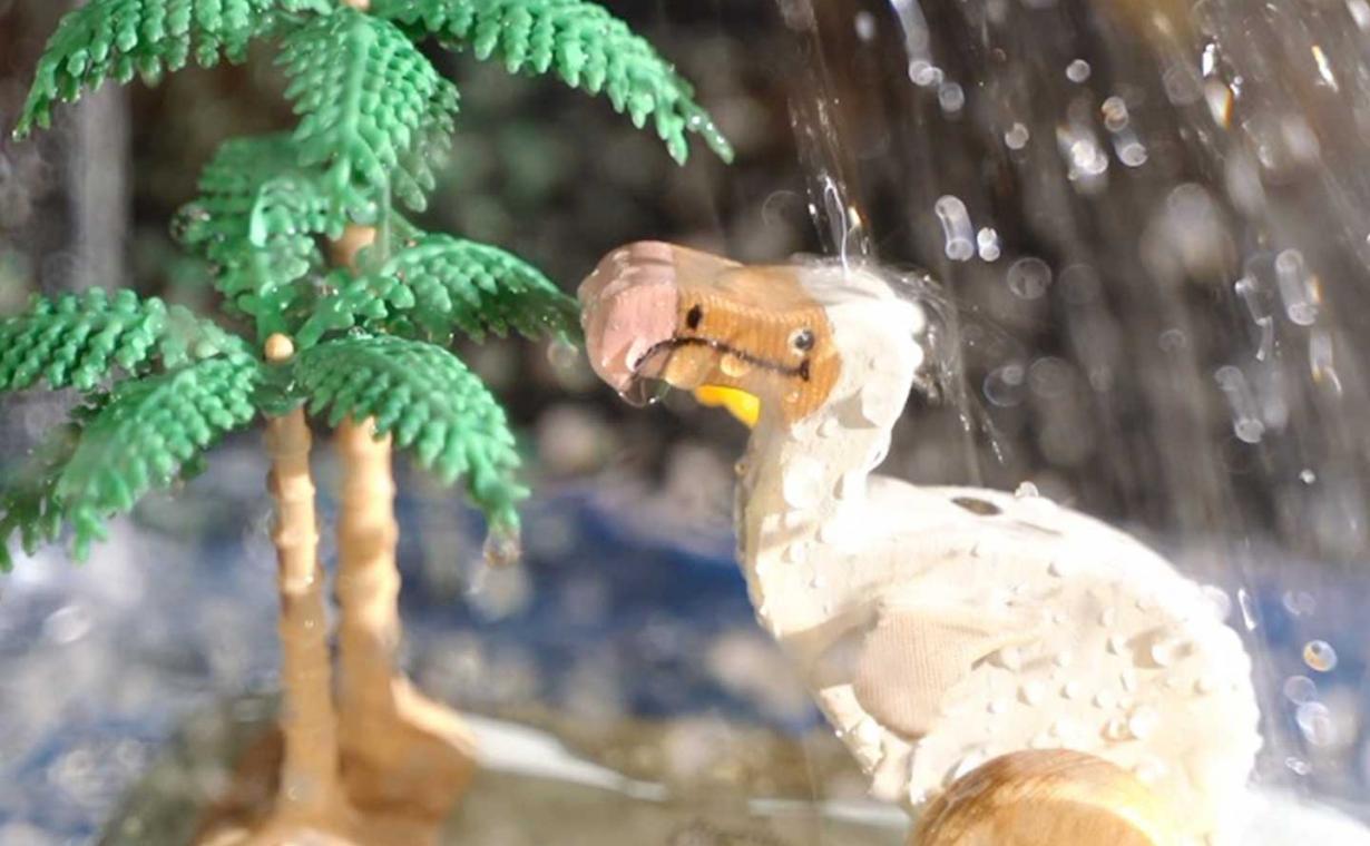 Spielzeugtier neben Spielzeugpalmen stehen im Regen.