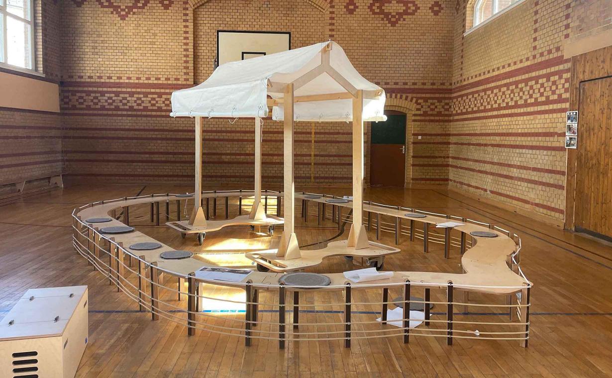 Aus Holzelementen zusammengesteckte Arche in einer Turnhalle.