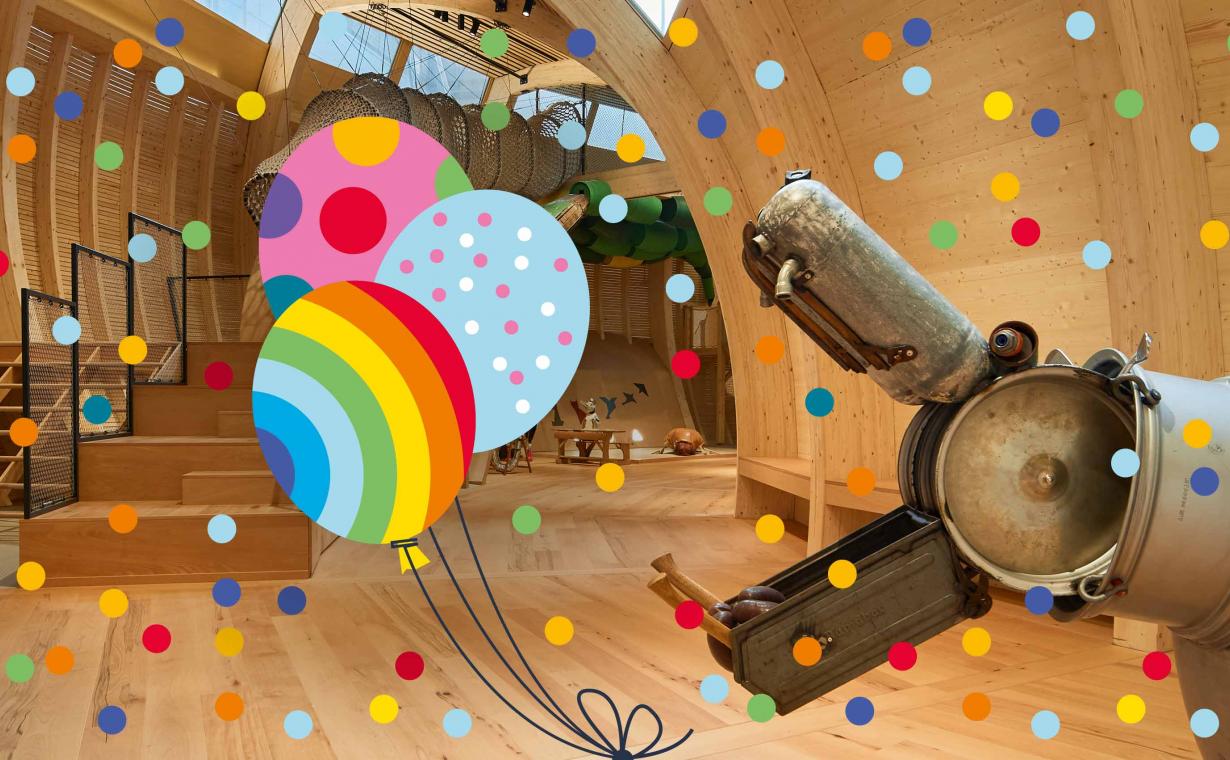 A hippo sculpture in the Children's Museum opens its mouth. Around it confetti and balloons as a graphic.