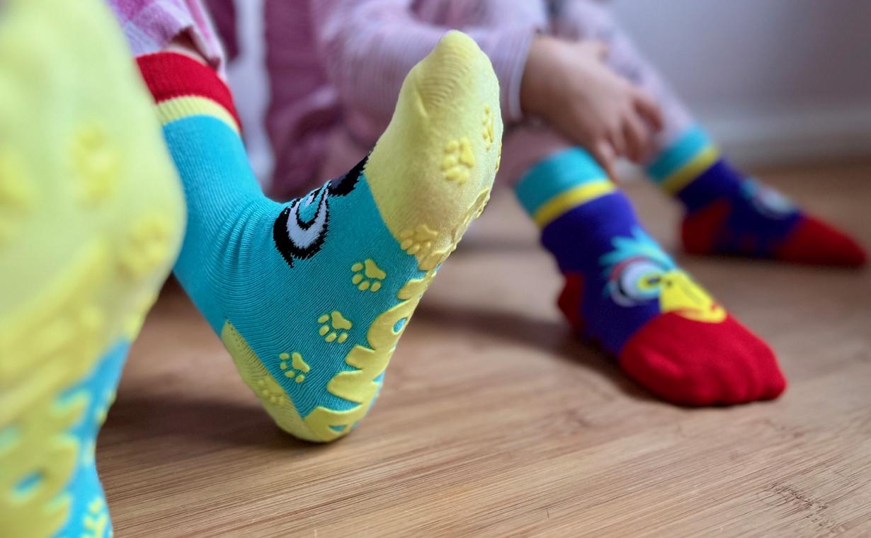 Vier Kinderfüße mit bunten Stoppersocken.